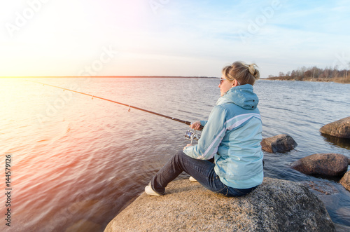 Girl sitting on a rock with a fishing rod