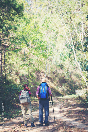 Backpackers couple hiking during looking a map with sticks. Couple travel concept.