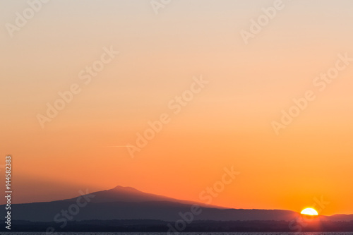 A minimalist sunset  with sun in the lower right angle  projecting light toward a mountain