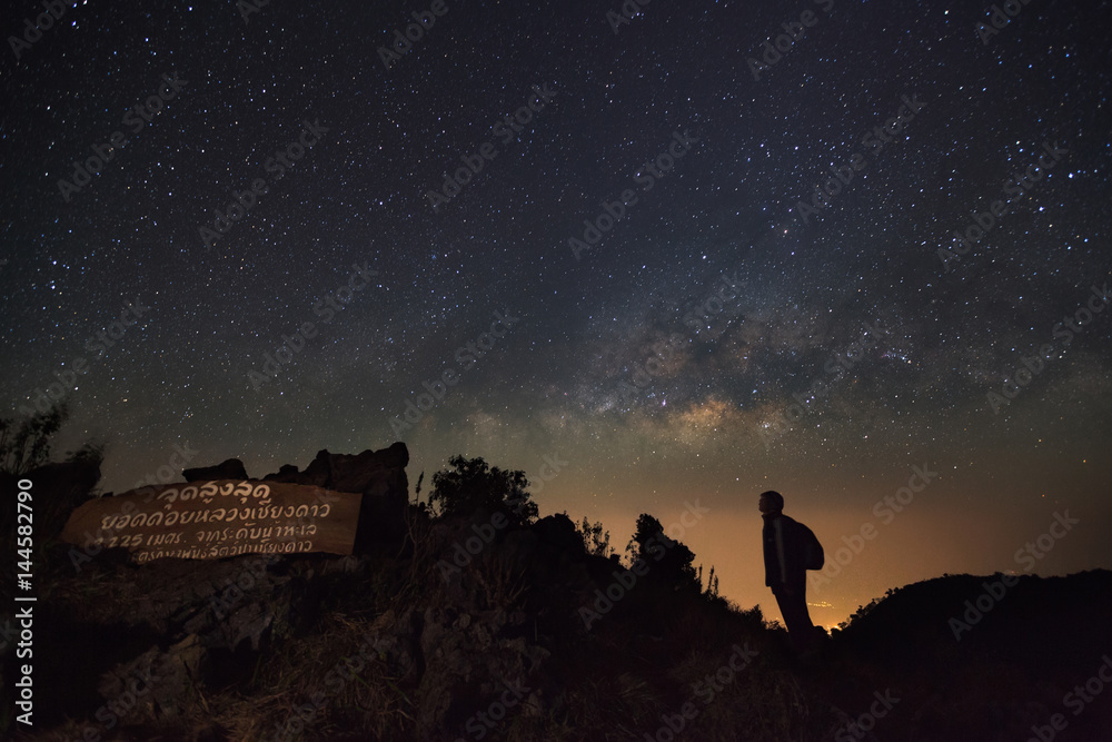 Fototapeta premium Doi Luang Chiang Dao, Chiang Mai - Febuary 13, 2016 : Milky way, Night sky with stars and silhouette of a standing man at Doi Luang Chiang Dao High moutaun top point signs.