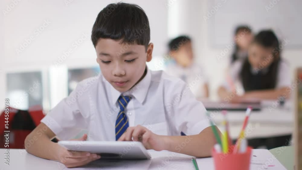 Portrait of happy little boy using computer tablet in school classroom Portrait of happy little boy using computer tablet in school classroom
