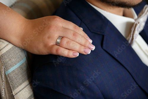 Bride's hand with wedding ring on groom's shoulder, wedding couple in love