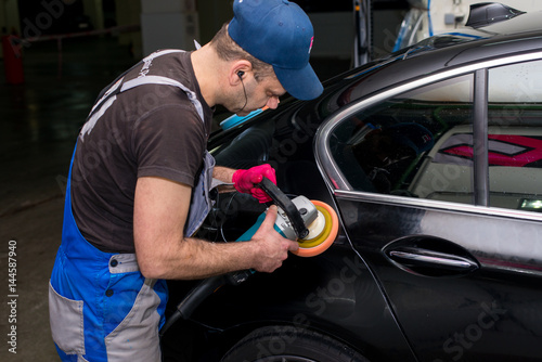 A man polishes a black car