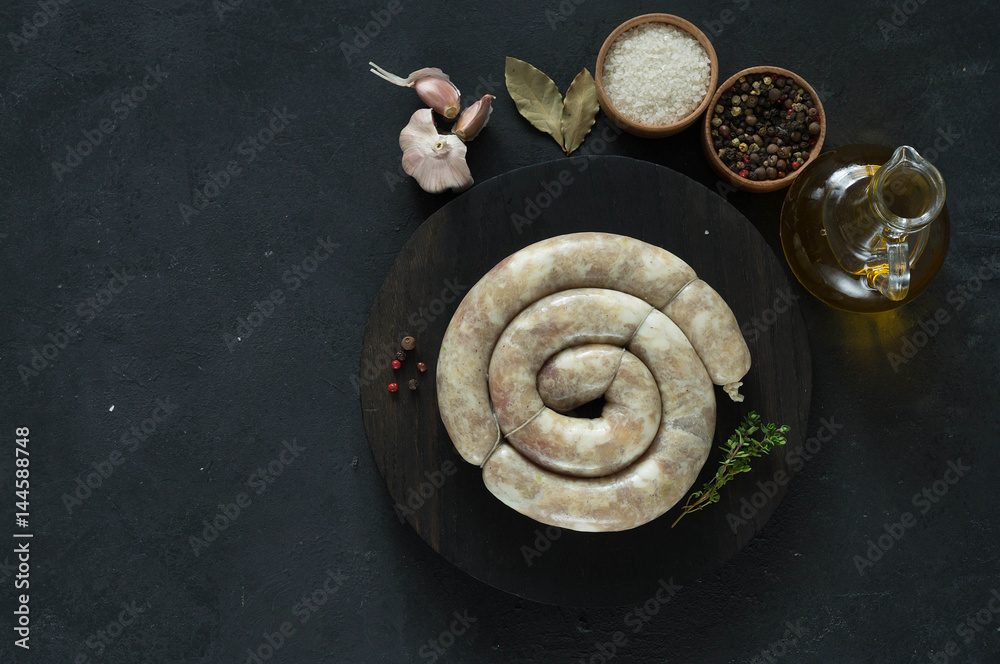 Raw homemade sausage on a black background with spices and herbs. copy space