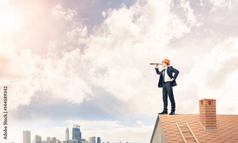 Engineer man standing on roof and looking in spyglass. Mixed med Engineer man standing on roof and looking in spyglass. Mixed med