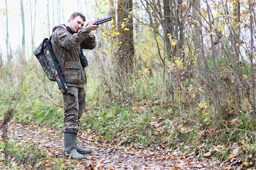 Man in camouflage and with guns in a forest belt on a spring hun