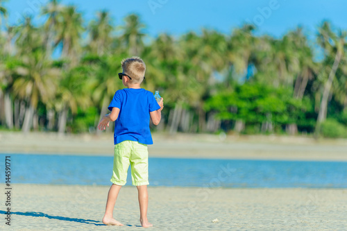 Portrait of a thirsty handsome boy in sunglasses drinking water on the desert tropical beach