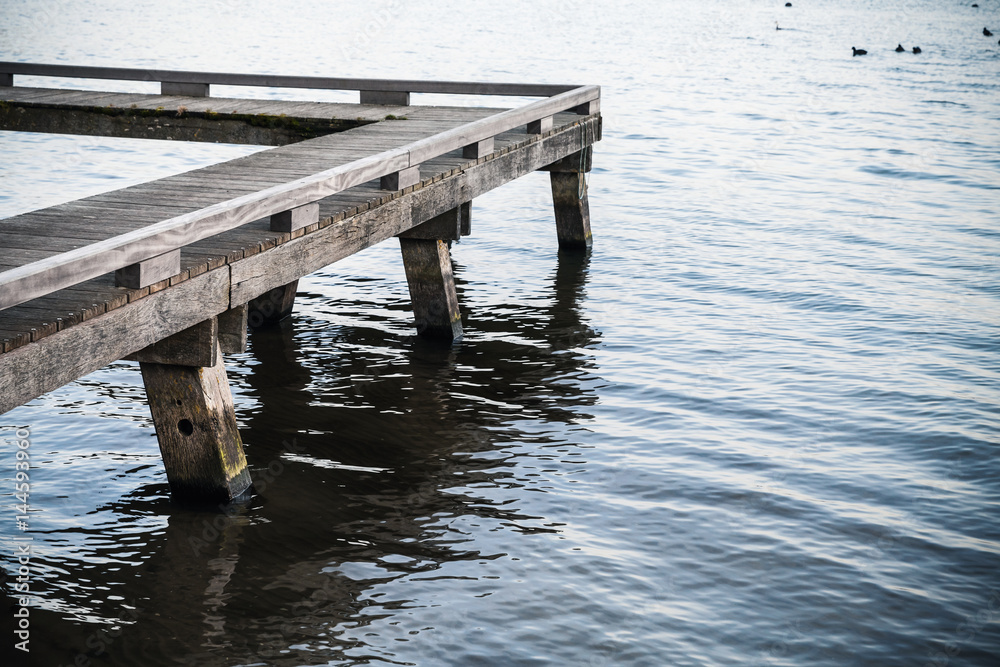 Corner of old wooden pier and blue lake