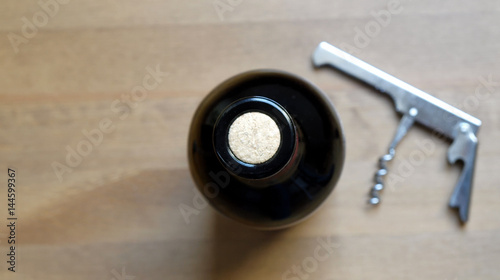 cenital view wine bottle and corkscrew bottle opener over timber surface