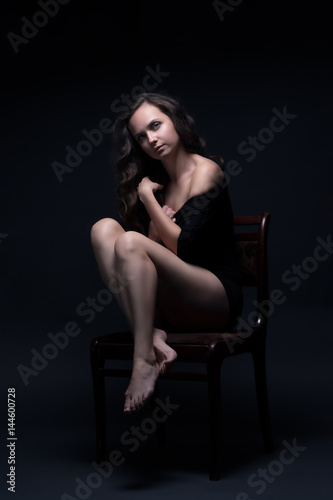 Young beautiful girl poses sexually on a black background