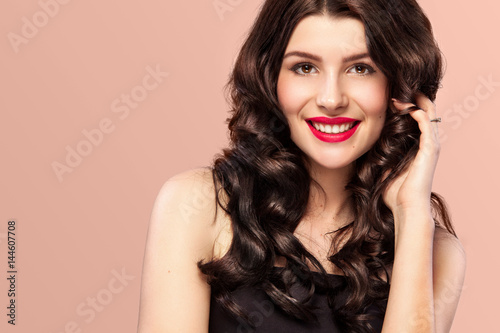 Sexy girl with long and shiny wavy hair . Beautiful model, curly hairstyle on orange background.