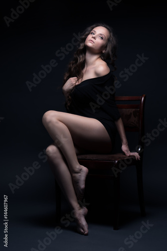 Young beautiful girl poses sexually on a black background © dimetradim