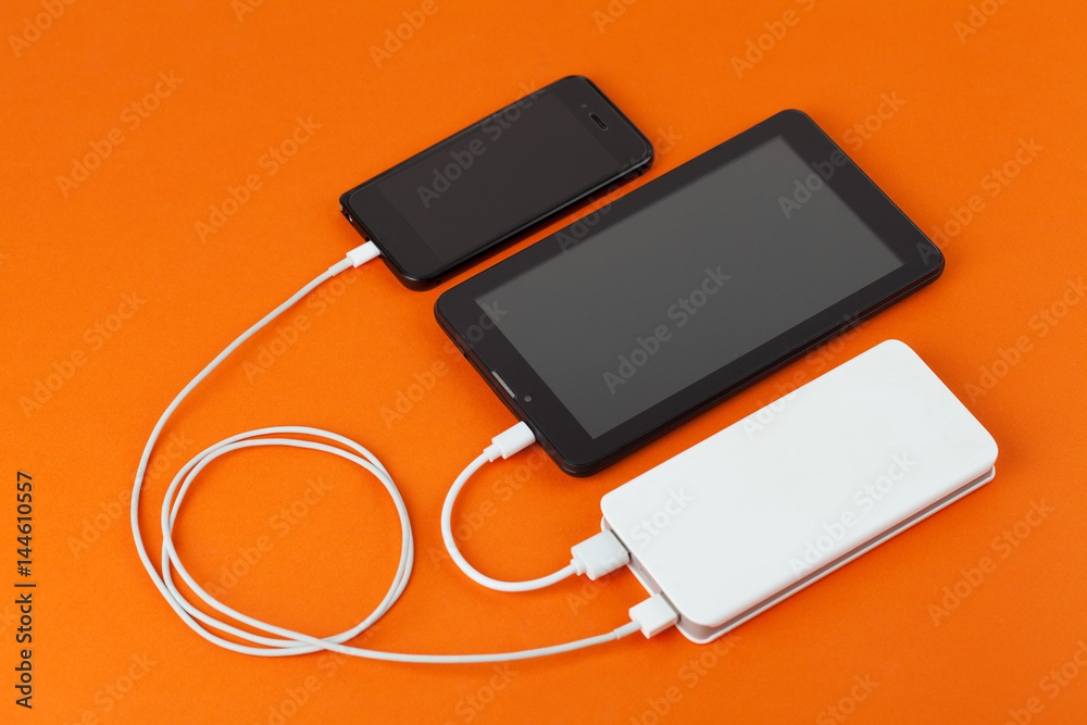 Two devices are charged from a power bank. Two devices are charged from a power bank.