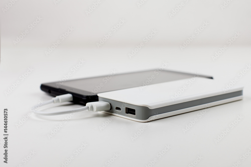 Tablet PC and power bank isolated on orange background. Top view. Tablet PC and power bank isolated on orange background. Top view.