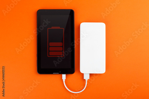 Tablet PC and power bank isolated on orange background. Top view.