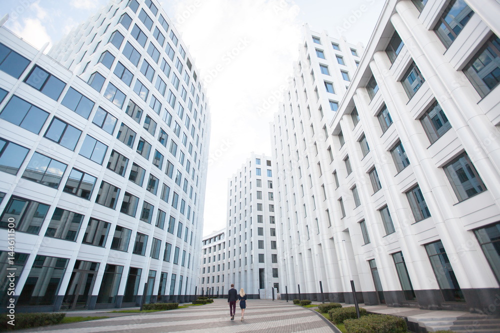 A man and a woman go into the distance, the white background of office building, business center. A man and a woman go into the distance, the white background of office building, business center.