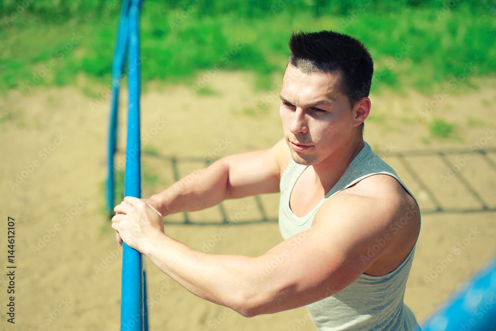 Obraz premium Sport, street workout concept - sportsman near the horizontal bar outdoors.
