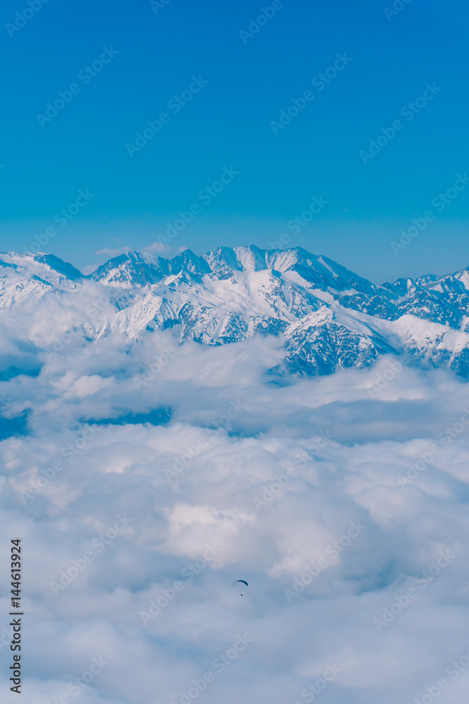 The paraglider flies over the clouds in the Caucasus Mountains