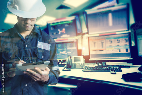 Double exposure of Engineer or Technician man in working shirt working with tablet in control room of oil and gas platform or plant industrial for monitor process, business and industry concept