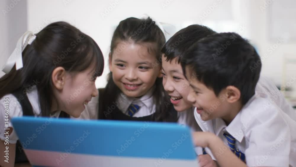 Happy group of children looking at computer in school classroom Happy group of children looking at computer in school classroom