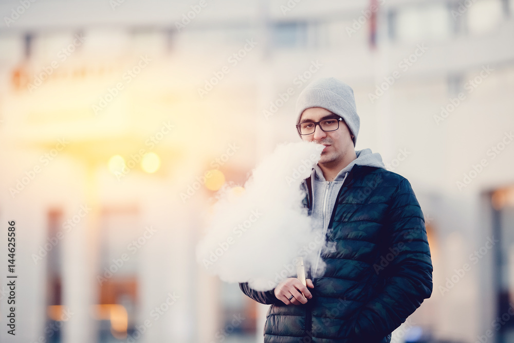 vaping man holding a mod device. cloud of vapor. Vape. high contrast and monochrome color tone. vaping man holding a mod device. cloud of vapor. Vape. high contrast and monochrome color tone.
