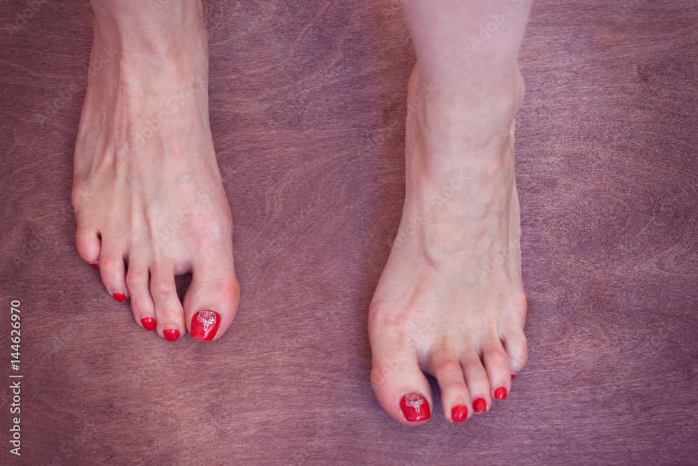 Legs of a young woman stand on a wooden background