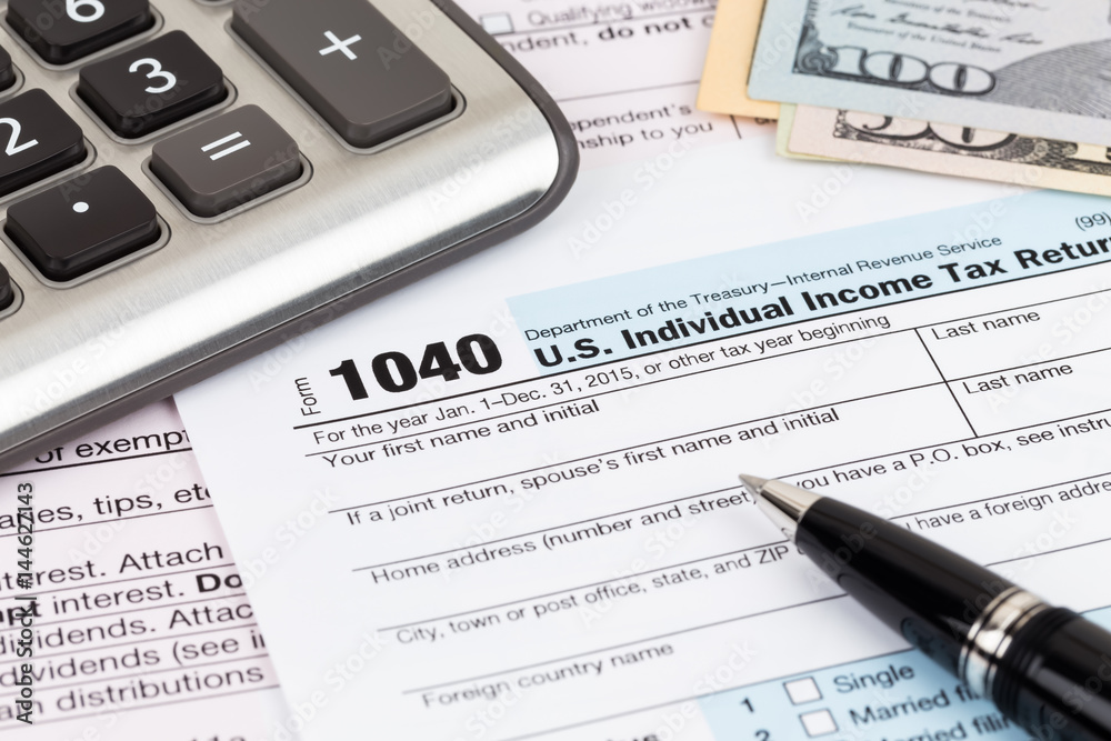 Tax form with calculator, pen, and dollar banknote
