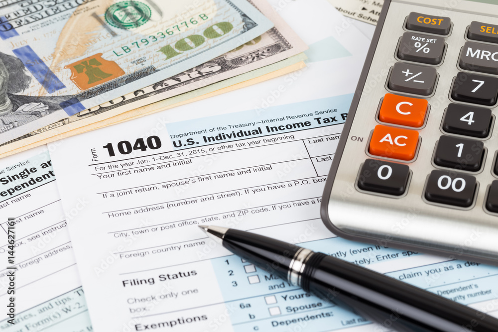 Tax form with calculator, pen, and dollar banknote Tax form with calculator, pen, and dollar banknote