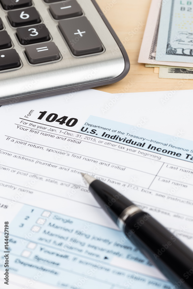 Tax form with calculator, pen, and dollar banknote Tax form with calculator, pen, and dollar banknote