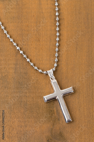 Silver cross with necklace on wooden background