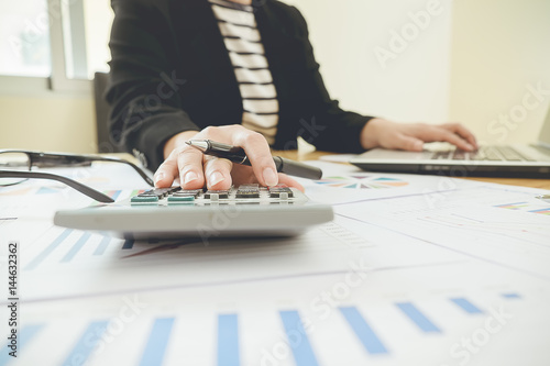 Asian Business woman using a calculator to calculate the numbers