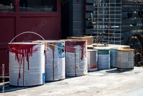 Old Paint Buckets Cans in front of an old garage