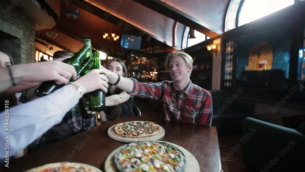 Friends drink beer and talk while waiting for pizza in a restaurant Friends drink beer and talk while waiting for pizza in a restaurant