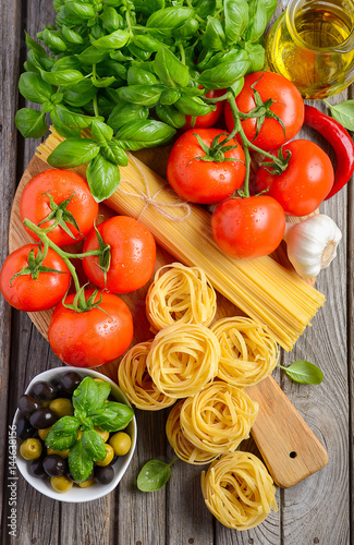 Pasta, vegetables, herbs and spices for Italian food on wooden background, top view