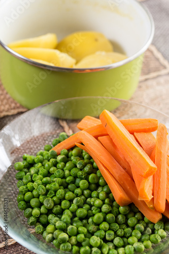 Peeled potatoes with cooked green peas and carrot