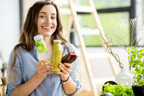 Beautiful happy woman sitting with drinks and healthy green food at home. Vegan meal and detox concept photo