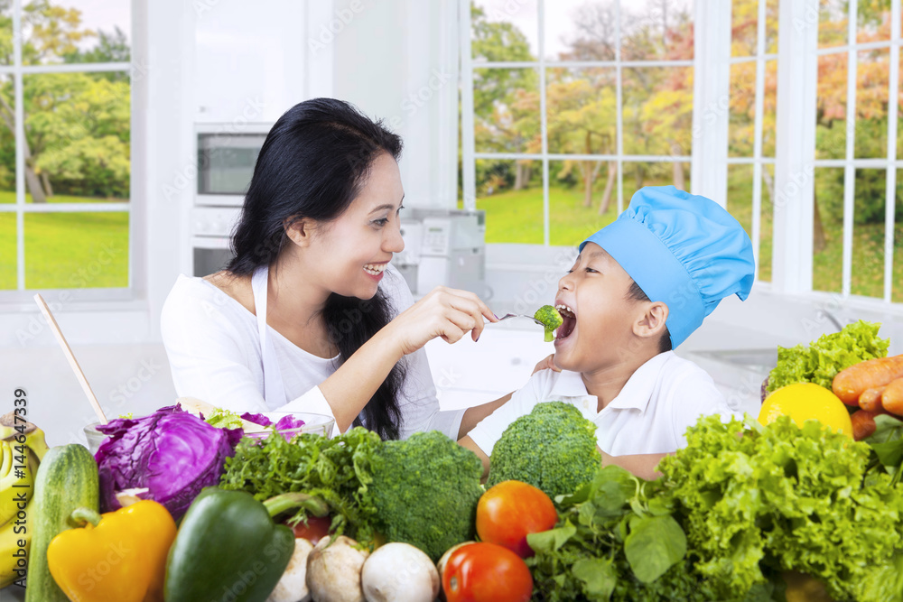 Happy mother gives her son fresh salad Happy mother gives her son fresh salad