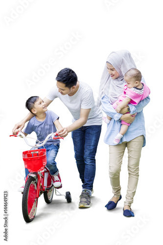 Parents teach their son to ride bicycle