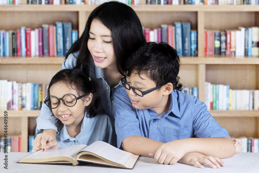 Pretty teacher teaches her students in the library Pretty teacher teaches her students in the library