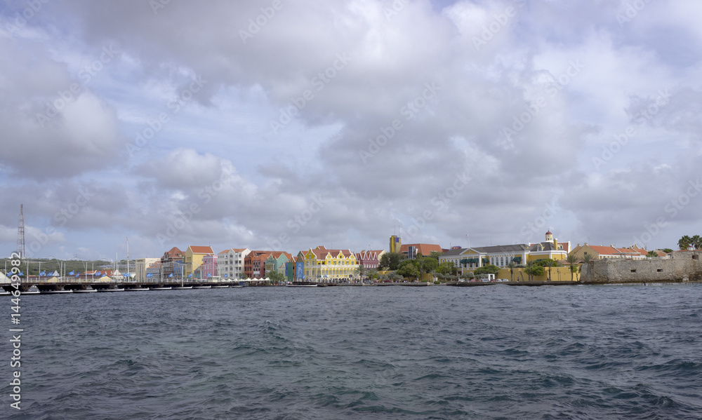 The Queen Emma pontoon bridge stretches across St Anna Bay in Willemstad, Curacao, looking along the pontoons toward the colorful buildings of Willemstad.