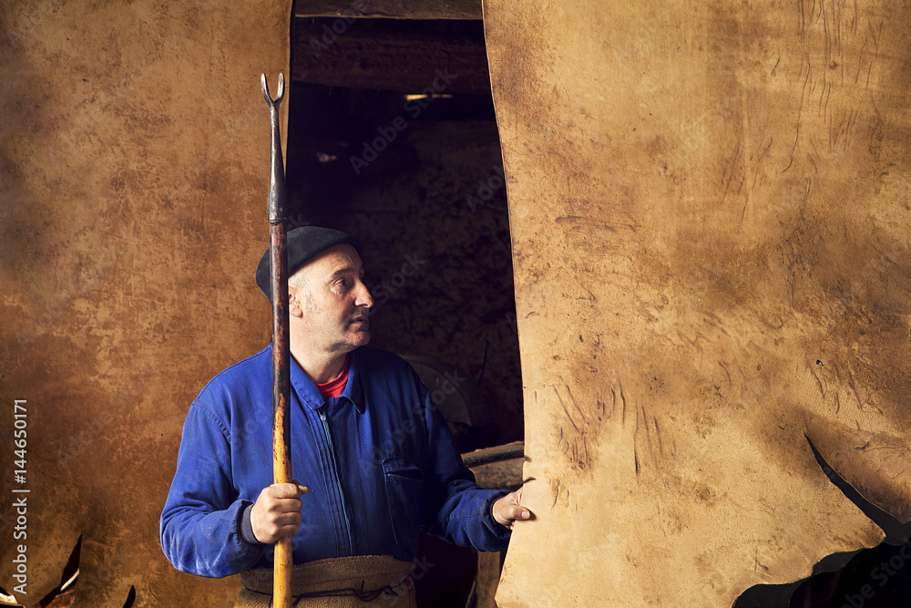 Fotografie tanner with leather in antique tannery