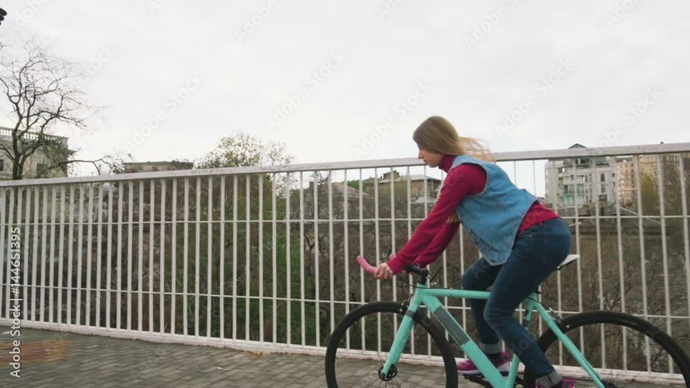 A young hipster girl riding a fixed gear bike at city centre, slow motion A young hipster girl riding a fixed gear bike at city centre, slow motion