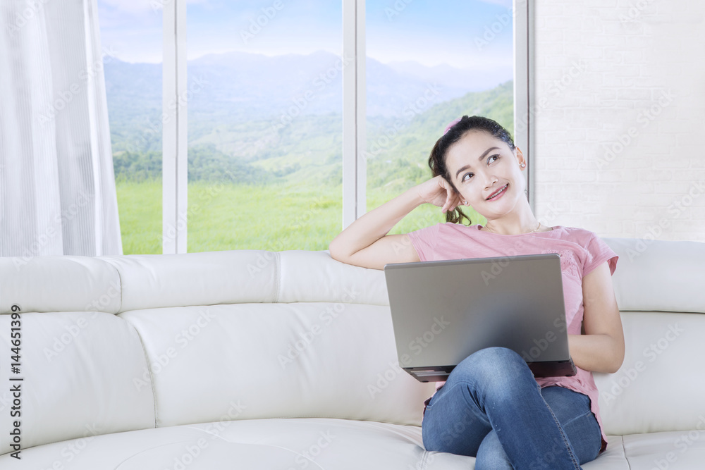 Naklejka premium Young woman daydreaming on sofa