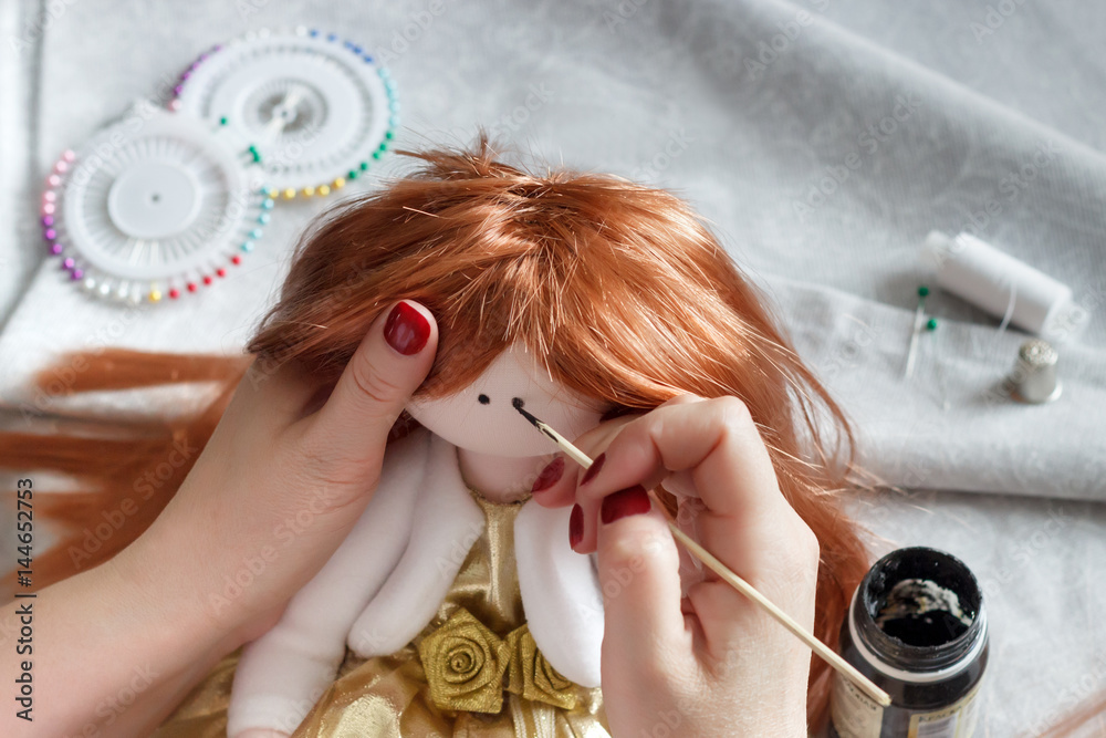 Doll making process. A woman draws the eyes of a doll Stock Photo