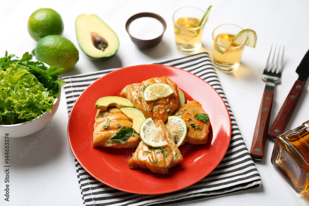 Plate of delicious tequila lime chicken with ingredients on white background
