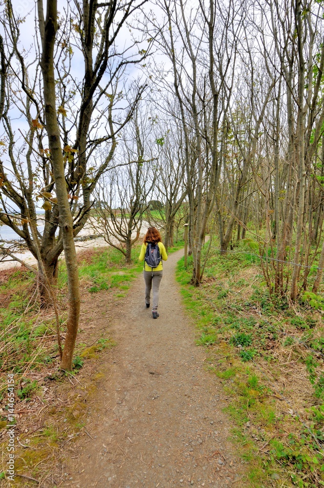 Une jeune femme pratique la randonnée sur le sentier de randonnée GR32 du Trégor en Bretagne Une jeune femme pratique la randonnée sur le sentier de randonnée GR32 du Trégor en Bretagne