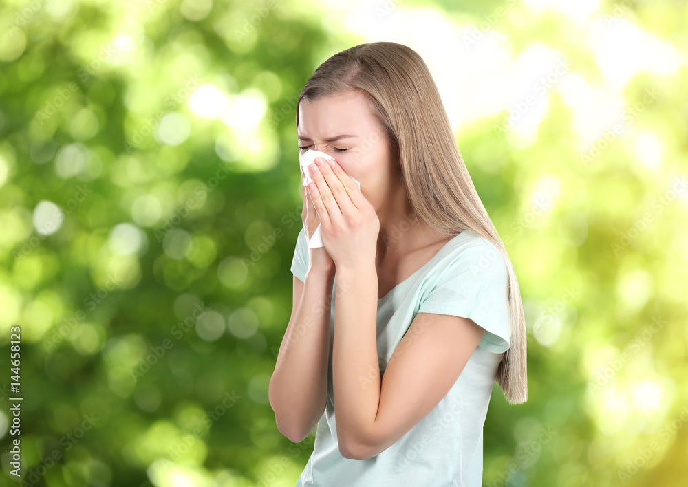 Seasonal allergy. Young woman with tissue on blurred background Seasonal allergy. Young woman with tissue on blurred background