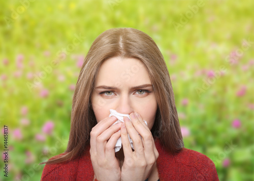 Young ill woman with tissue on white background