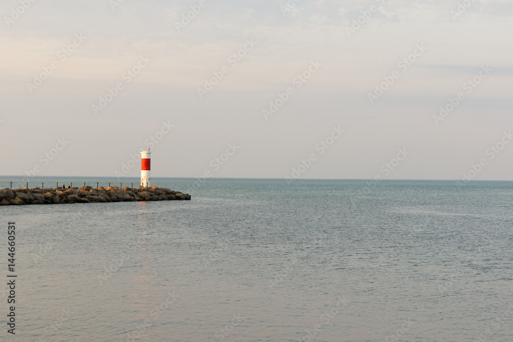 Wide angle view of a red and white lighthouse on Lake Ontario near Rochester, New York