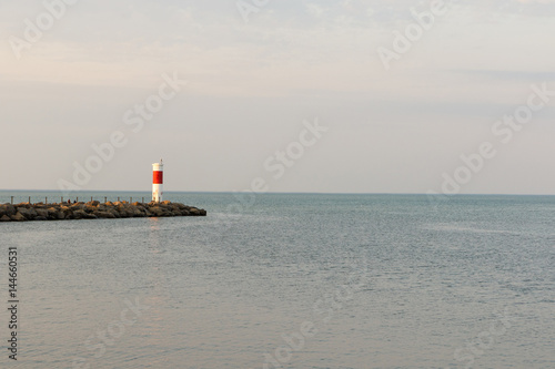 Wide angle view of a red and white lighthouse on Lake Ontario near Rochester, New York